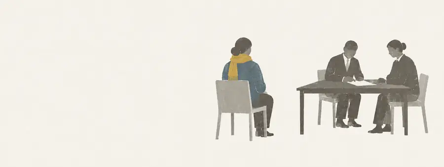 En forælder sidder for sig selv over for to fagpersoner ved et bord.
